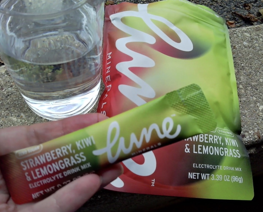 Customer photo: a Strawberry, Kiwi & Lemongrass stick pack held next to a glass of water